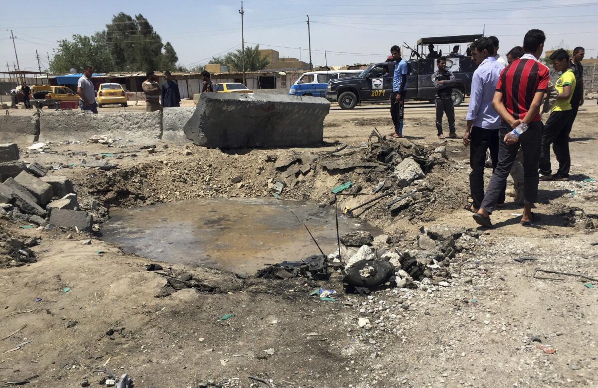 Civilians inspect a crater caused by a car bombing at an open-air market in Baghdad on April 30, 2016.