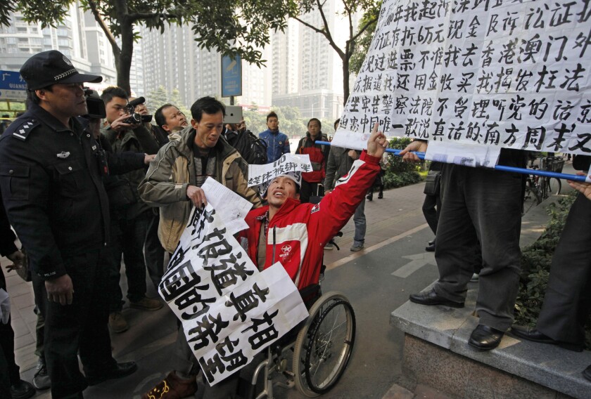 In this January 2013 photo, a policeman eyes a supporter, in a wheelchair, of Southern Weekly at the newspaper's headquarters in Guangzhou, China.