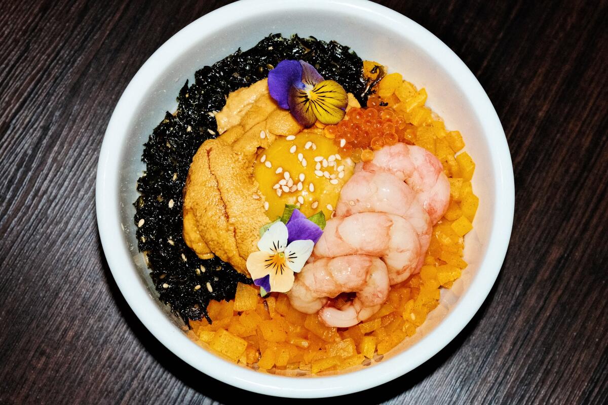An overhead photo of seafood bibimbap from Danbi in Koreatown with uni, ikura, black rice and marinated shrimp.