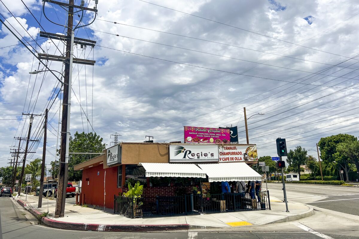 A building at a corner with signs that say "Rocio's" and "Tamales, champurrado y cafe de olla"