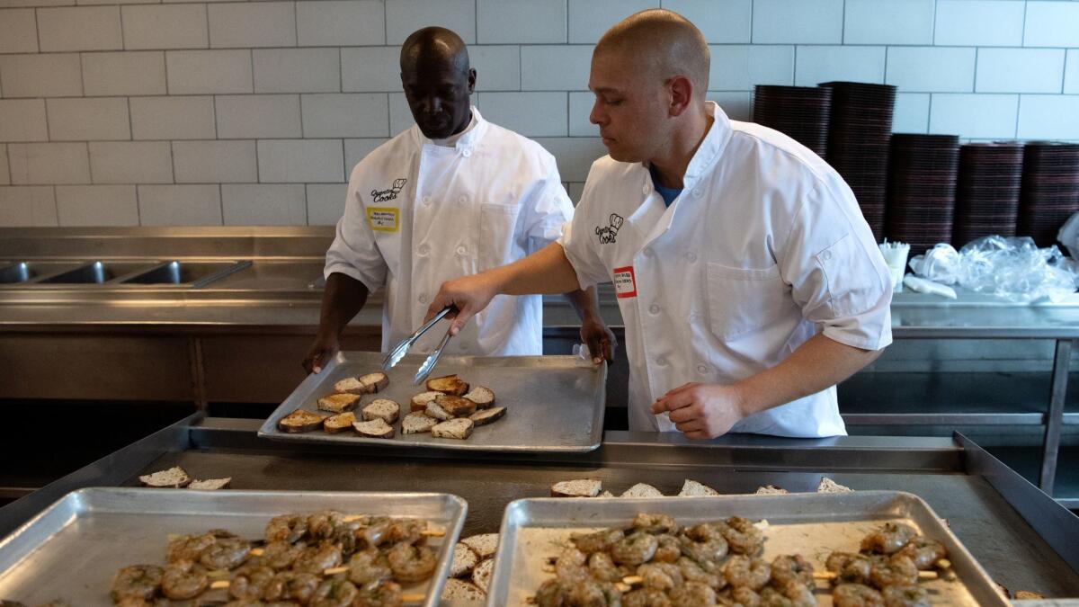 Ron Simmons, left, and Kerry Rudd, work on preparing the first of four courses to be served at the Quentin Cooks graduation dinner at San Quentin State Penitentiary.