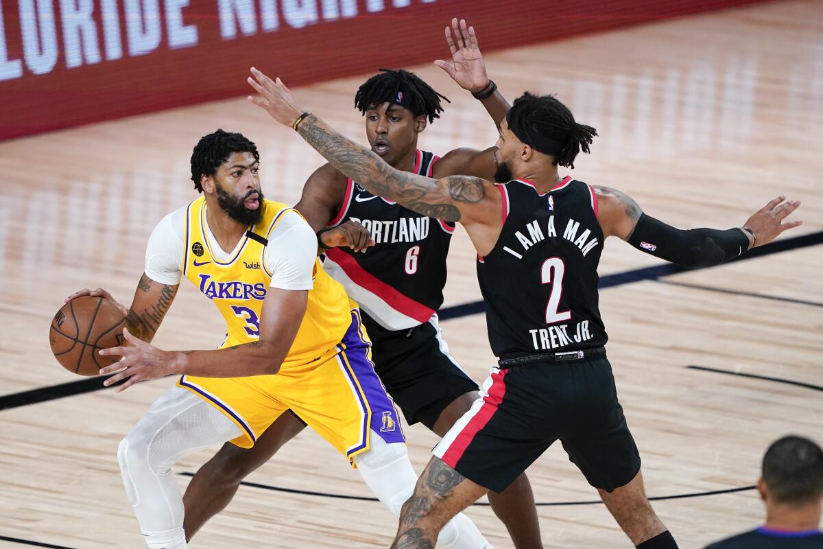 Lakers' Anthony Davis looks for a way past Portland Trail Blazers' Jaylen Hoard and Gary Trent Jr.