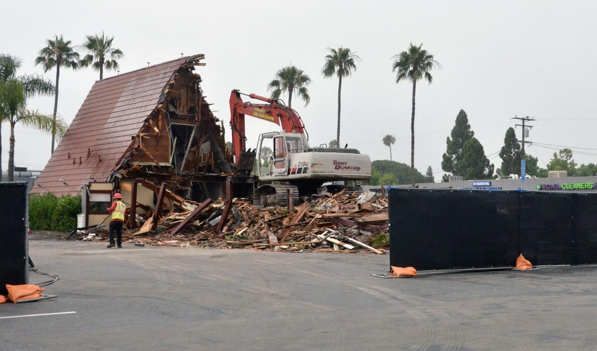 Businesses remained open as an excavator demolished the building at 333 E. 17th St. in Costa Mesa.