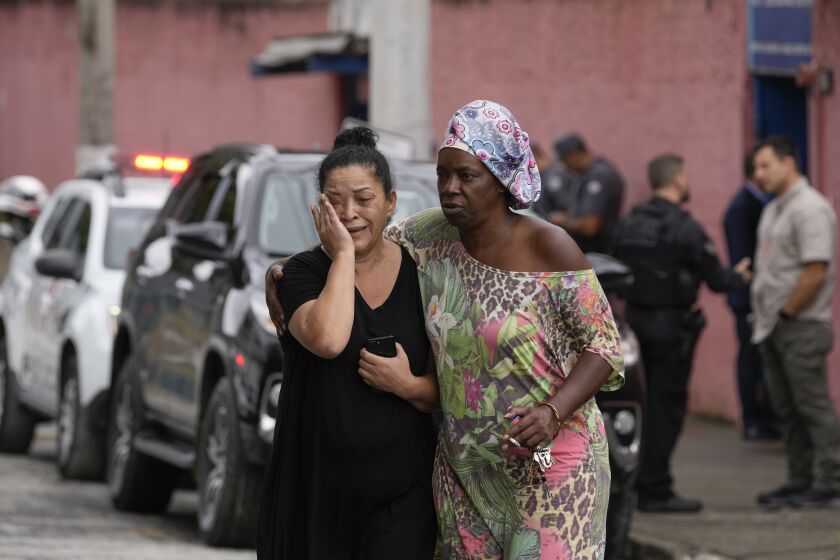 Silvia Palmieri, who is the mother of a teacher who survived a stabbing attack at the Thomazia Montoro school, left, leaves the school comforted by a friend in Sao Paulo, Brazil, Monday, March 27, 2023. According to authorities, one teacher died and a 13-year-old attacker was detained after stabbing both students and teachers. (AP Photo/Andre Penner)