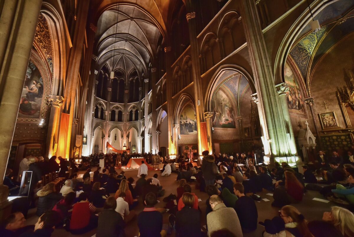 In this photo dated Saturday, Dec. 5, 2015, and provided by Taize, people pray at an interfaith service for world leaders to curb global warming during a multi-lingual service at Church St Ignatius in Paris, France. The cold hard numbers of science haven't spurred the world to curb runaway global warming. So as climate negotiators struggle in Paris, some scientists who appealed to the rationale brain are enlisting what many would consider a higher power: the majesty of faith. (Marie Renaux/Taize via AP)