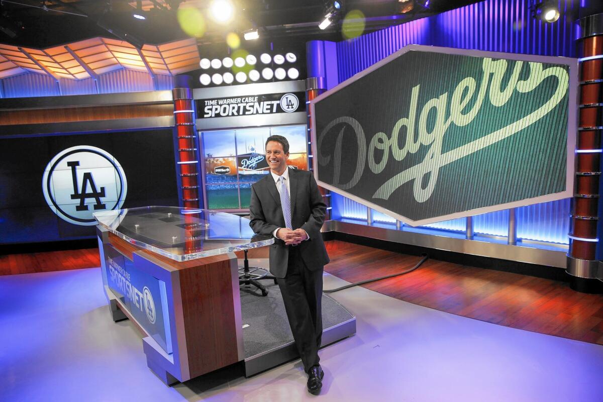 Dodgers fans had hoped the media megamergers would be completed in time for the start of the new baseball season. Above, John Hartung of SportsNet LA, the Dodgers channel carried only by Time Warner Cable.