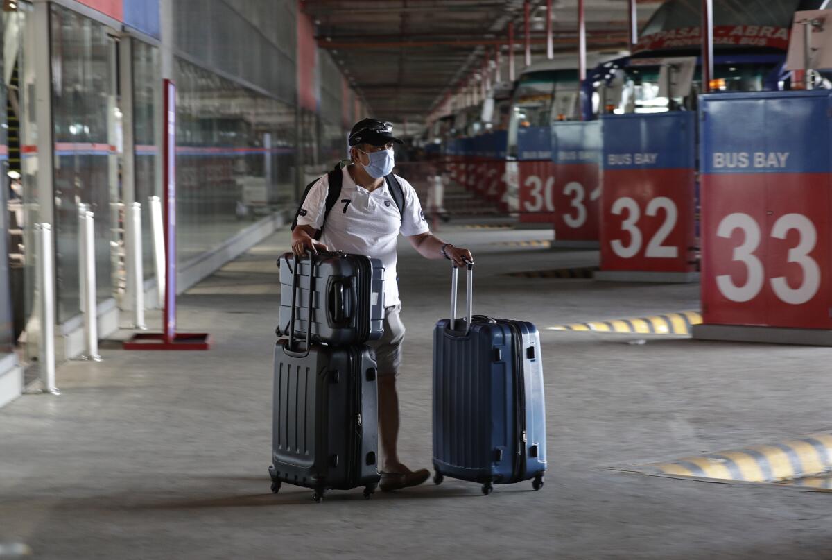 A Philippine seafarer pushes his bag at a bus terminal after spending weeks quarantined on a ship.