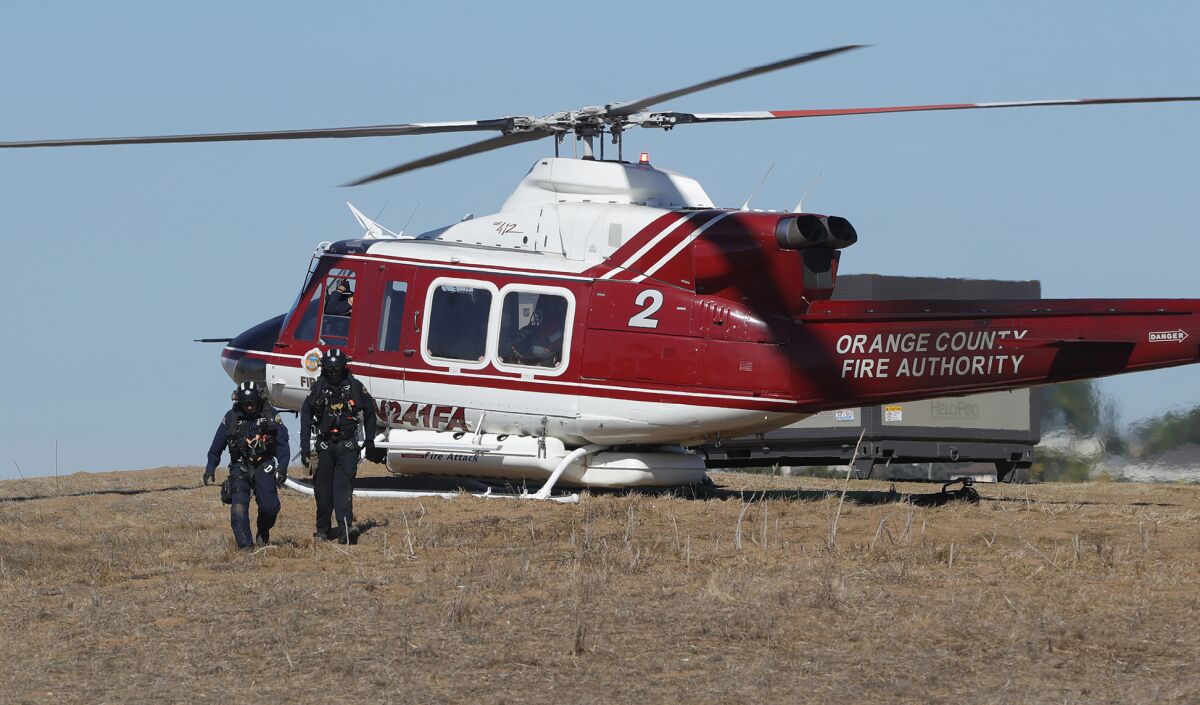 Two crew members arrive from OCFA helicopter 2 during a presentation of the new HeloPod dip tank water refilling system.