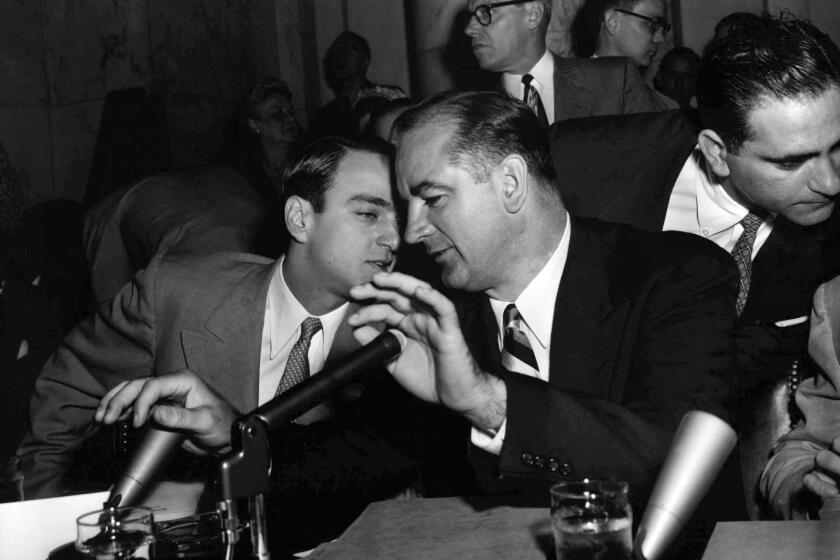 U.S. Sen. Joseph McCarthy holds both hands over microphones as he speaks to his chief counsel, Roy Cohn, during a hearing of the Senate Investigations Subcommittee in Washington on April 22, 1954.