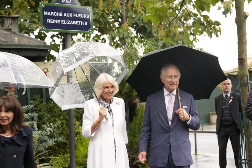 Britain's King Charles III and Queen Camilla pose at a plaque named after his late mother, Queen Elizabeth II at the Flower Market Thursday, Sept. 21, 2023 in Paris. The royal couple's trip started Wednesday with a ceremony at Arc de Triomphe in Paris and a state dinner at the Palace of Versailles. King Charles will rejoin French President Emmanuel Macron in front of Notre-Dame Cathedral to see the ongoing renovation work aimed at reopening the monument by the end of next year, after it was devastated by a fire in 2019.(AP Photo/Christophe Ena; Pool)