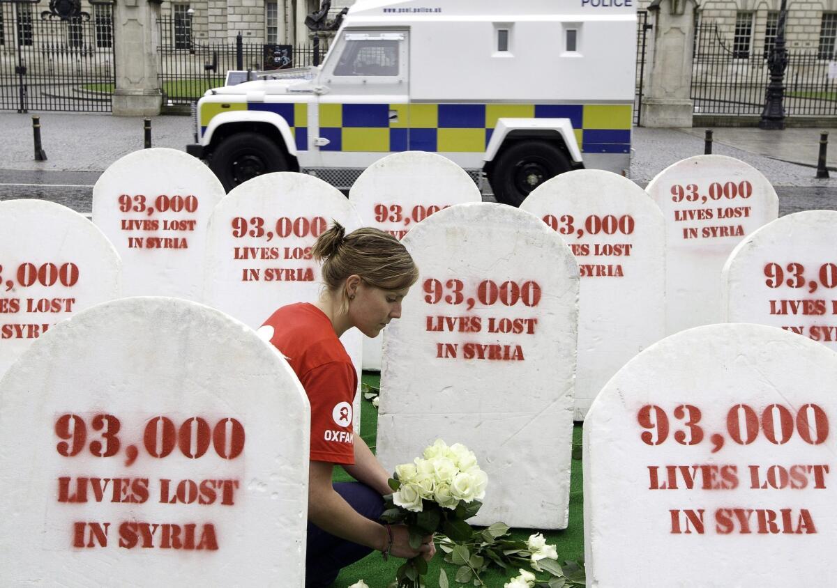 Oxfam protesters outside the Group of 8 summit in Lough, Northern Ireland, place flowers around mock gravestones symbolizing the 93,000 killed in Syria.