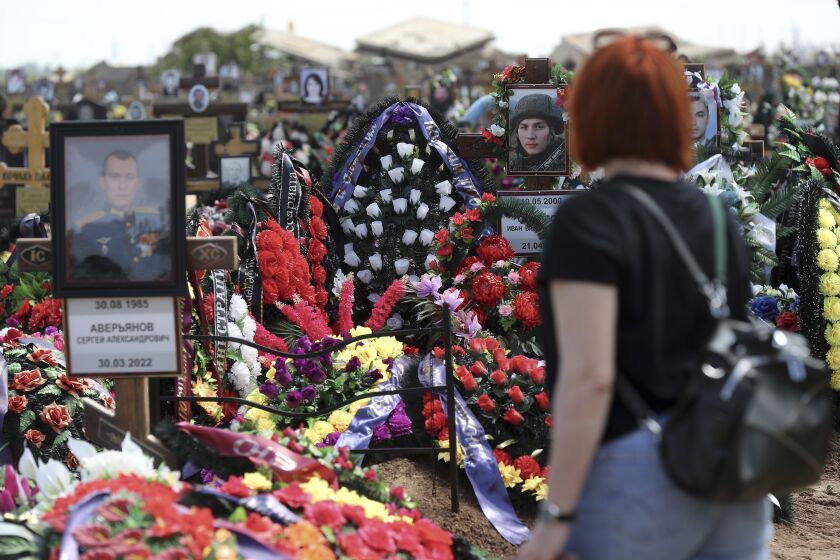 FILE - A woman at a cemetery in Volzhsky, outside Volgograd, Russia, on May 26, 2022, looks at the graves of Russian soldiers killed in the war in Ukraine. Some experts say that Europe's largest conflict since World War II could drag on for years. (AP Photo, File)