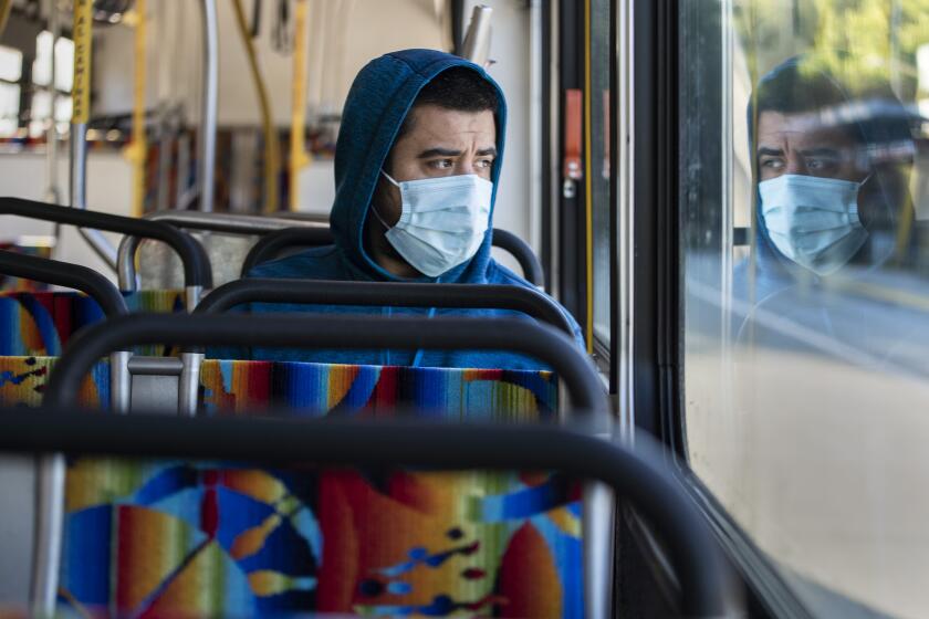 WOODLAND HILLS, CALIF. -- FRIDAY, MARCH 27, 2020: Danny Armada sits with his own reflection in the window of an early morning Orange Line bus in Woodland Hills, Calif., on March 27, 2020. The coronavirus pandemic is causing ridership on LA Metro trains and busses to plummet. (Brian van der Brug / Los Angeles Times)