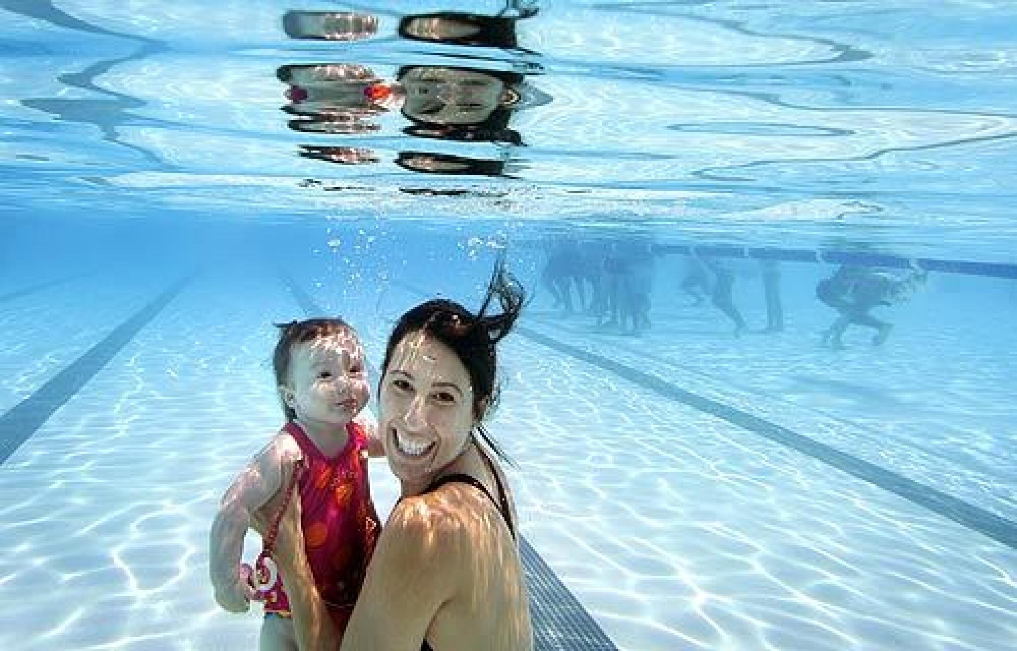 Janet Evans and her 8-month-old daughter, Sydney, take a dip into the John C. Argue pool at Exposition Park to kick off the LA84 Learn-to-Swim Program on the first day of summer. The program aims to teach kids to swim and foster love of water and reduce drownings.