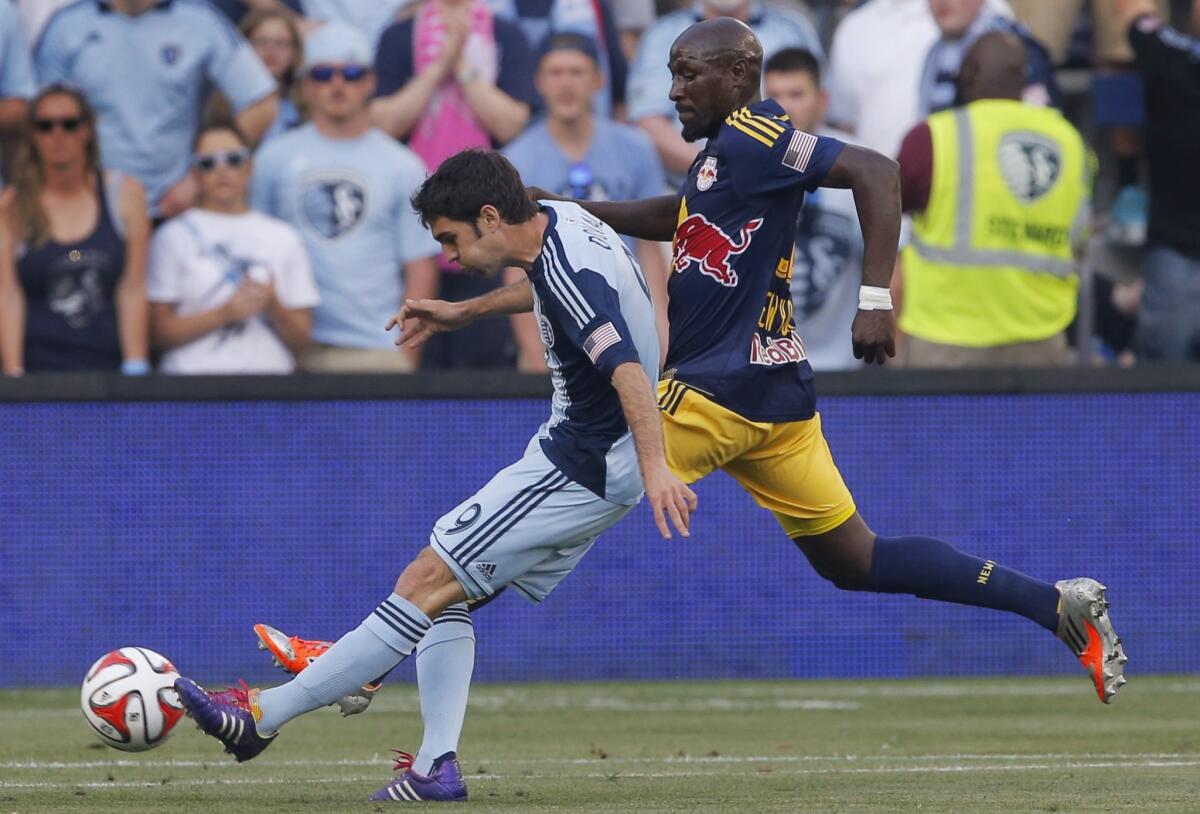 Sporting Kansas City midfielder Antonio Dovale scores a goal while being covered by Ibrahim Sekagya in the first half of a match Tuesday in Kansas City, Kan.