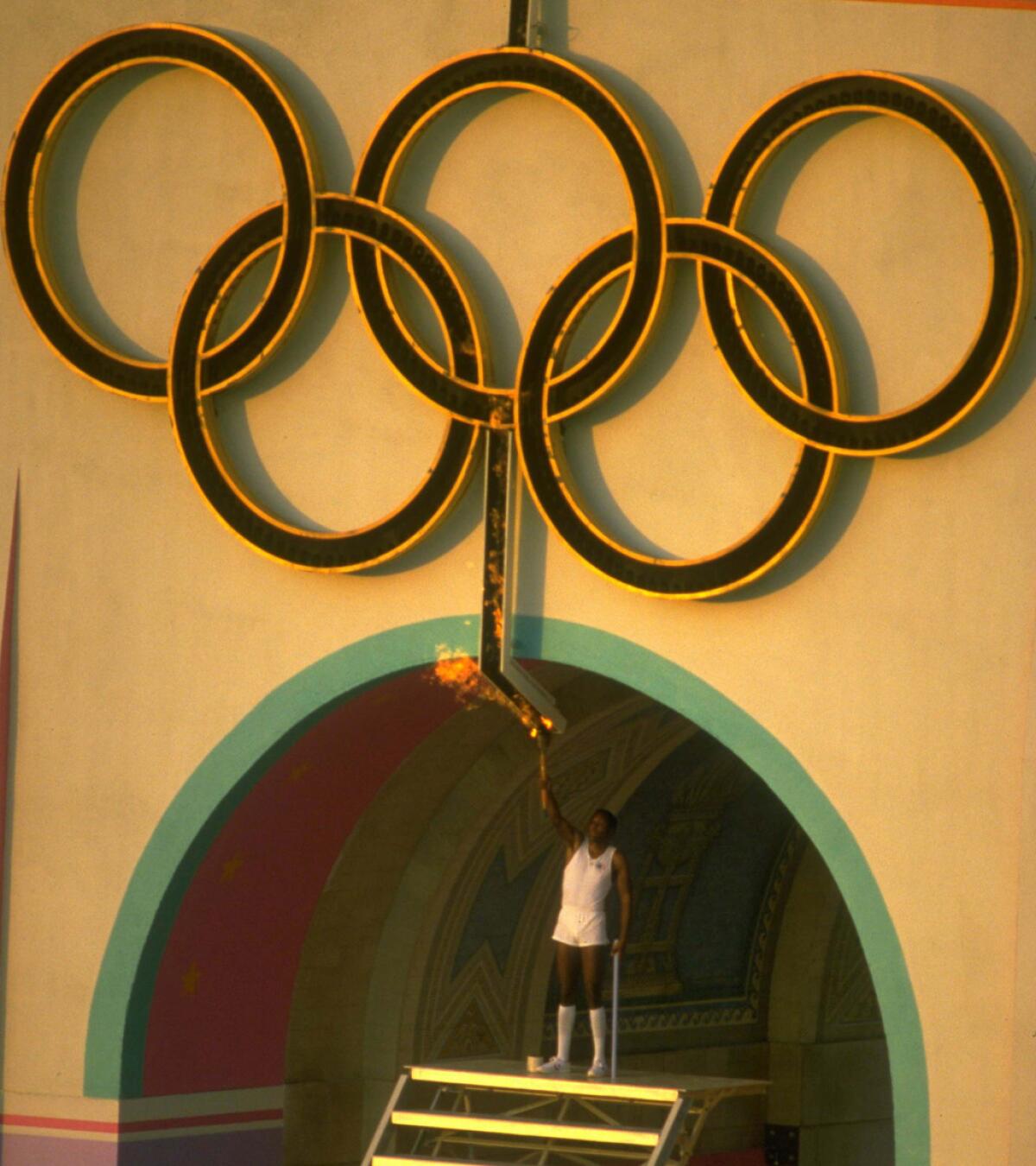 Rafer Johnson lights the Olympic flame at the opening ceremonies for the 1984 Los Angeles Olympics at the Coliseum.