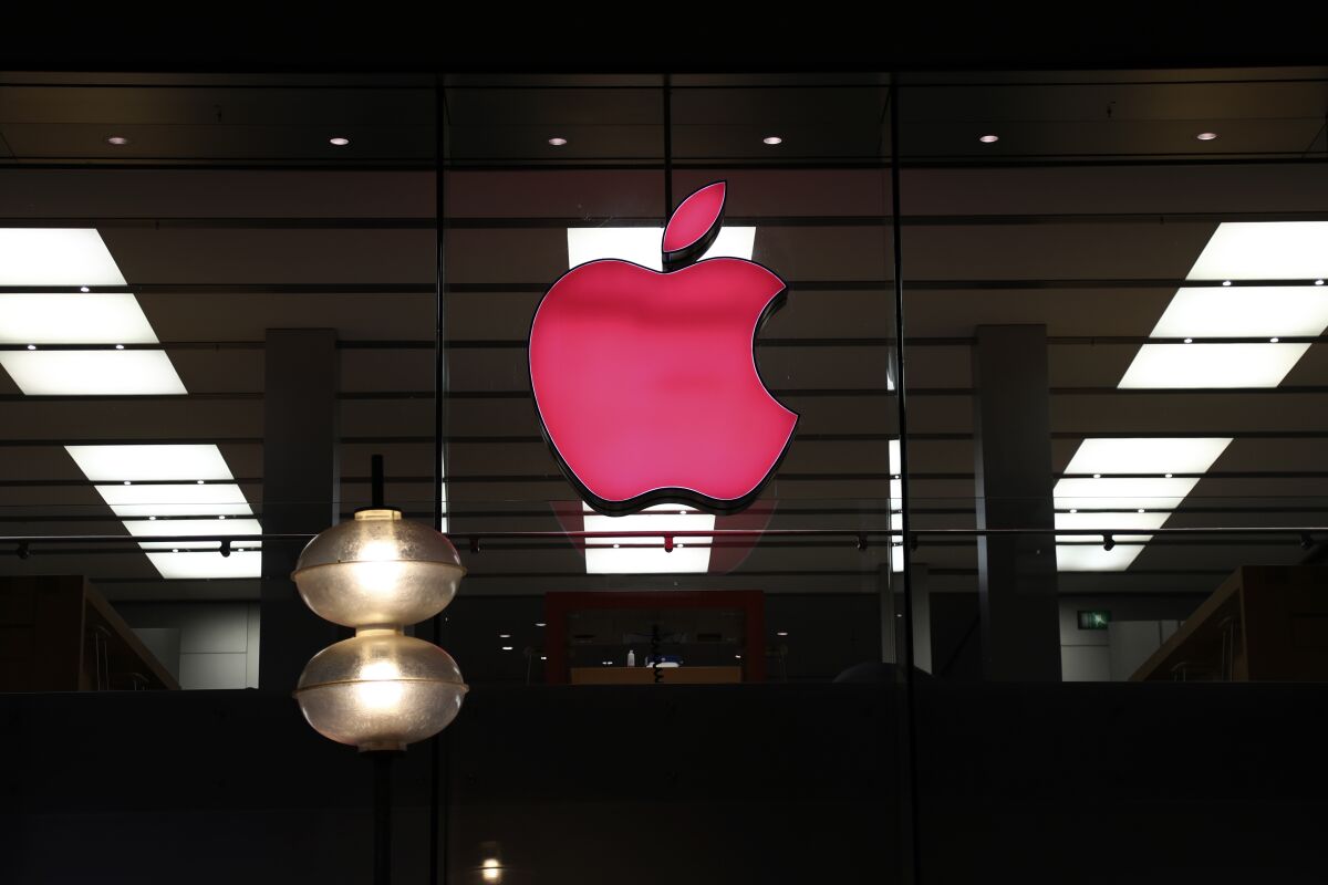 FILE - In this Sunday, Dec. 6, 2020 file photo, the logo of Apple is illuminated at a store in the city center of Munich, Germany. Apple is stepping up privacy for app users, forcing developers to be more transparent about data collection and warning they could be removed if they don't comply with a new anti-tracking measure, a company executive and regulators said Tuesday Dec. 8, 2020. (AP Photo/Matthias Schrader, File)