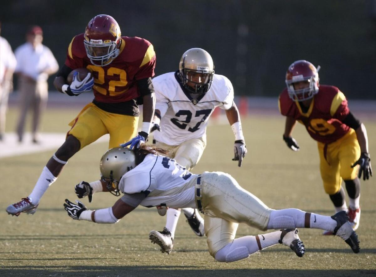 Glendale Community College football's Marquise McGuire, left, tires to leap over an Antelope Valley College defender.