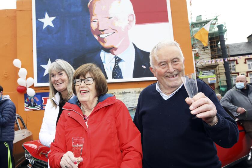 Brendan Blewitt, a cousin of US Presidential candidate Joe Biden, and his sister Breege Bourke celebrate in anticipation of the results of the US election as Biden edges closer to victory over Donald Trump, at a mural of Biden in his ancestral home of Ballina, Co. Mayo, Ireland, Saturday, Nov. 7, 2020. (AP Photo/Peter Morrison)