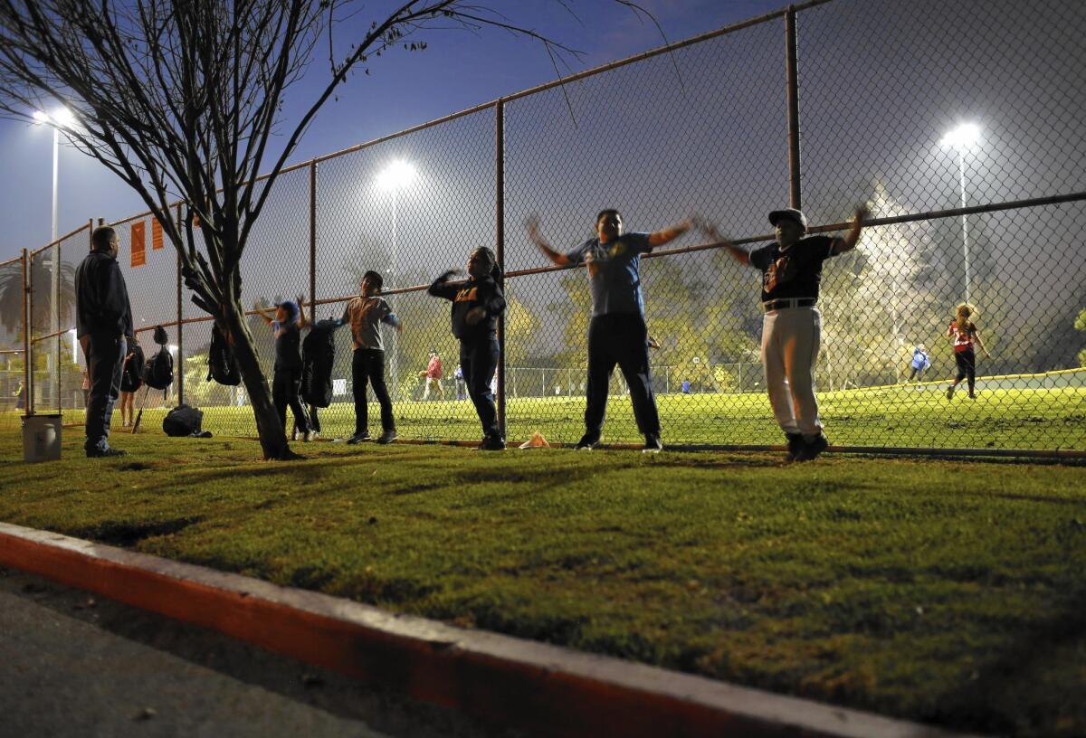 Members of east Hollywood's L.A. Bulldogs do jumping jacks on the strip of grass between the Lemon Grove Recreation Center baseball field and the parking lot.