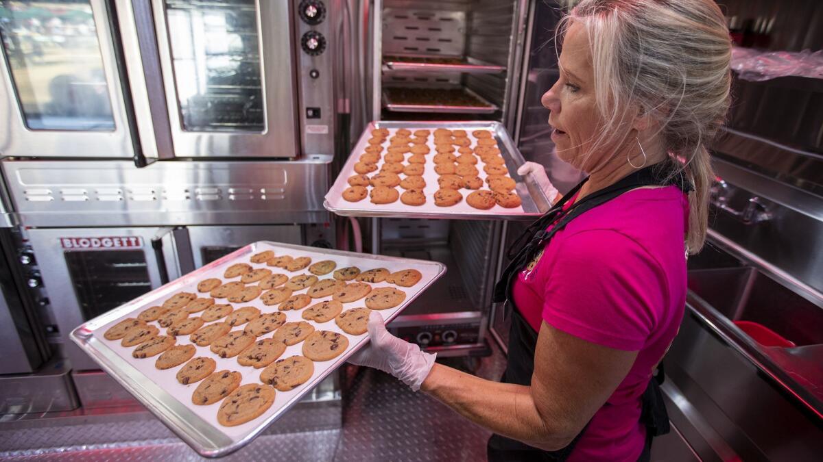 Cathy Johnson of Cathy’s Cookies takes freshly baked chocolate chip cookies out of the oven in her mobile kitchen at the Orange County Fair.