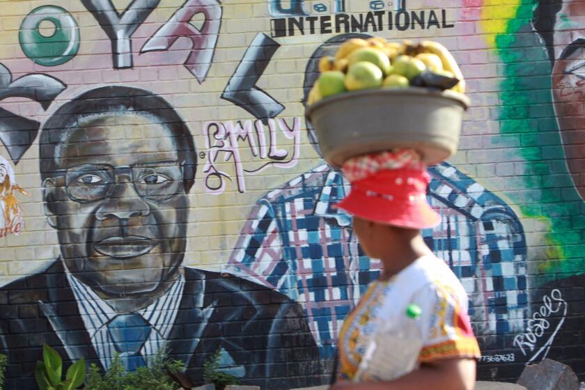 A woman walks past a painting of Zimbabwean President Robert Mugabe in Harare, Monday, Nov, 20, 2017. Lawmakers with the ruling Zanu pf party gathered to meet on the fate of long time President Robert Mugabe, who has refused efforts to step down. (AP Photo/Tsvangirayi Mukwazhi)
