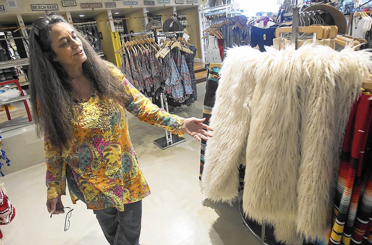 Merrilee Madrigal looks at the coats her daughter Felicia designed at Merrilee's Swimwear in Laguna Beach.