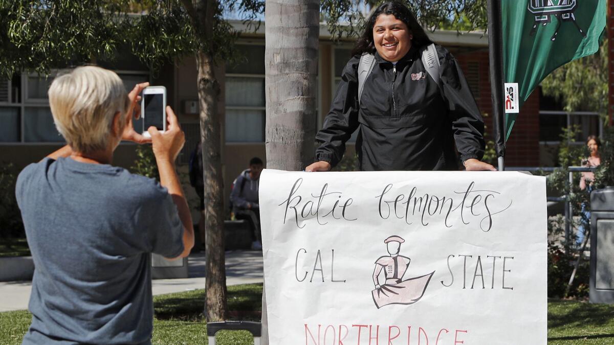 Softball player Katie Belmontes smiles in front of her banner as she participates in a National Signing Day ceremony at Costa Mesa High School on Wednesday.