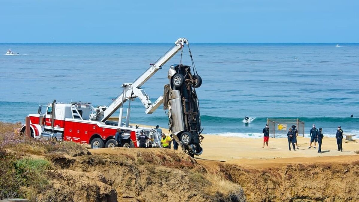 Crews recover the wreckage of a pickup that crashed over the edge of Sunset Cliffs