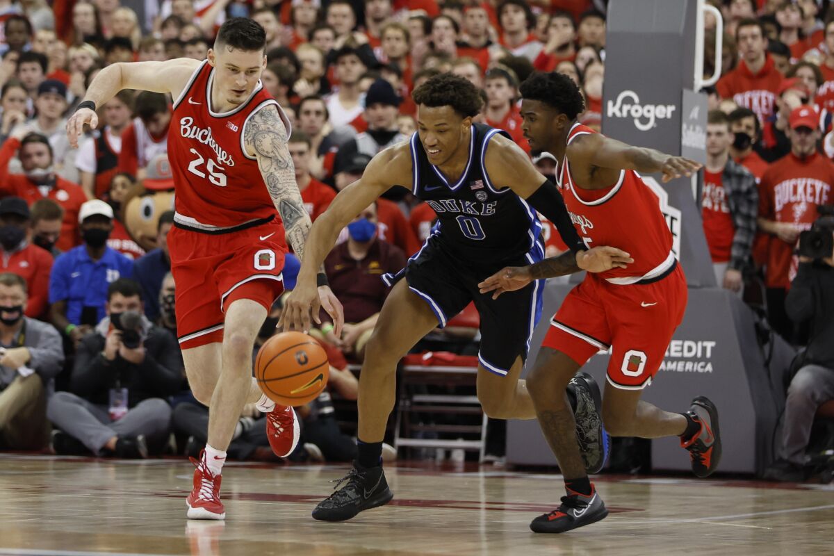 Ohio State's Kyle Young, left, and Jamari Wheeler, right, and Duke's Wendell Moore chase a loose ball during the first half of an NCAA college basketball game Tuesday, Nov. 30, 2021, in Columbus, Ohio. (AP Photo/Jay LaPrete)