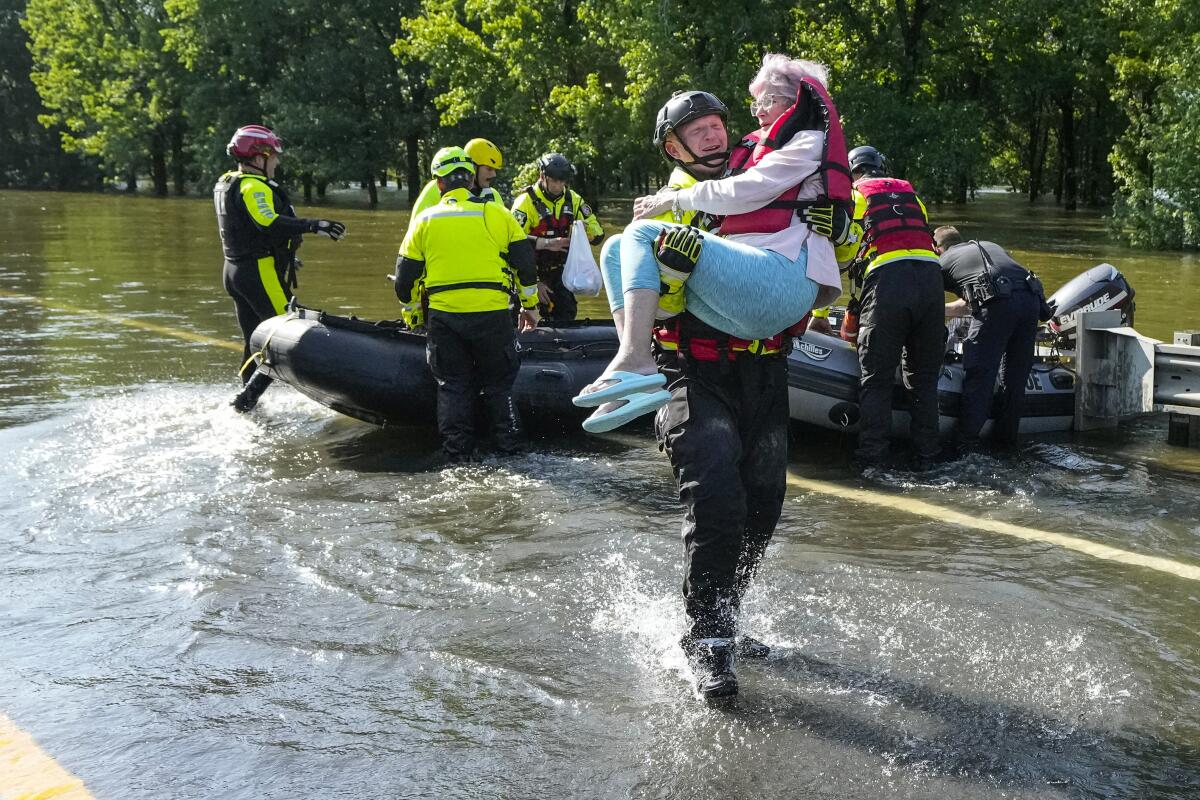 A rescuer carries a woman through floodwaters.
