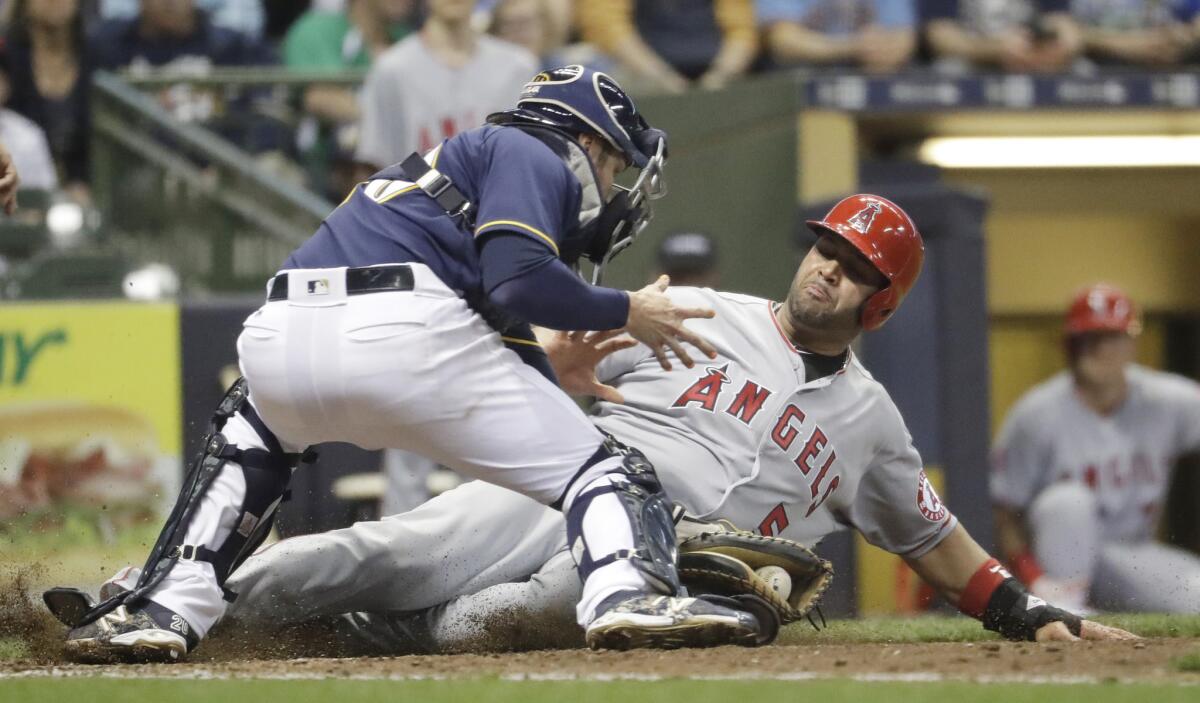 Angels first baseman Albert Pujols slides safely under the tag of Brewers catcher Jonathan Lucroy during the eighth inning.