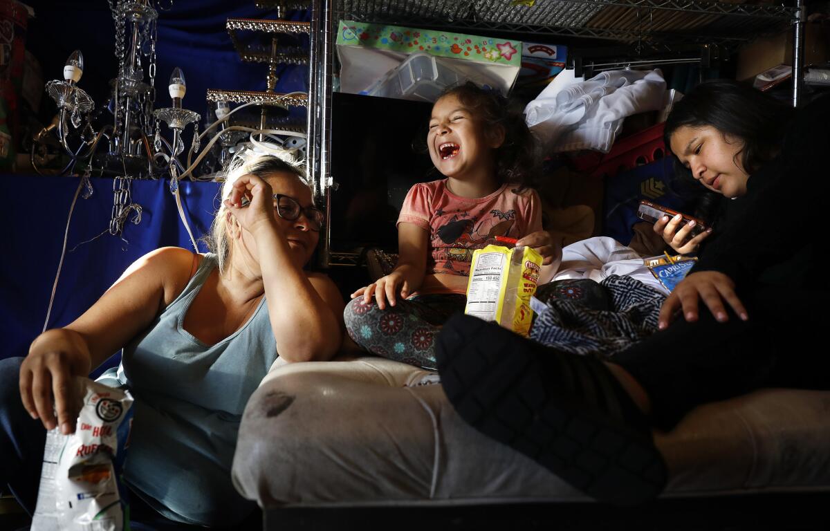 Emely Ramirez, 6, center, spends time with her mom Brenda Ramirez, 35, left, and sister Brenda Lopez, 17, right, at the family's party decoration shop in South L.A.
