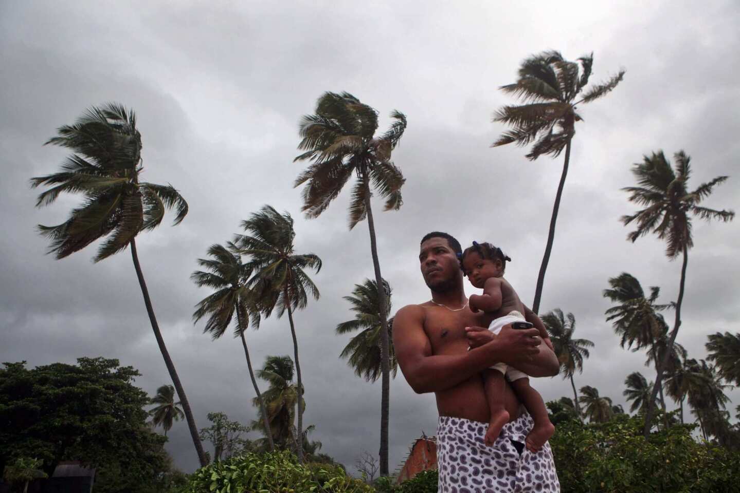 A man and child watch strong swells on Bahoruco beach in Barahona, Dominican Republic, before the expected arrival of Tropical Storm Isaac.