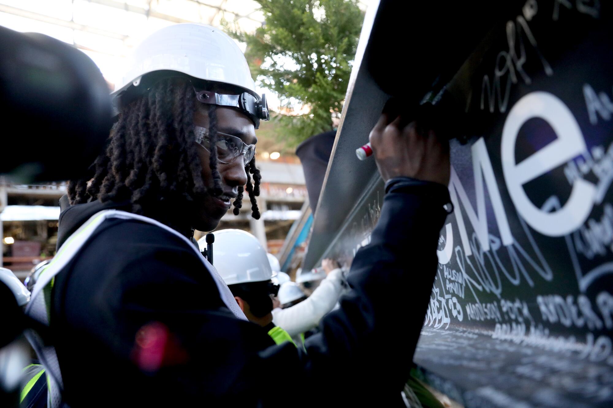 Clippers guard Terance Mann signs a steel beam that was placed atop the Intuit Dome on Tuesday.