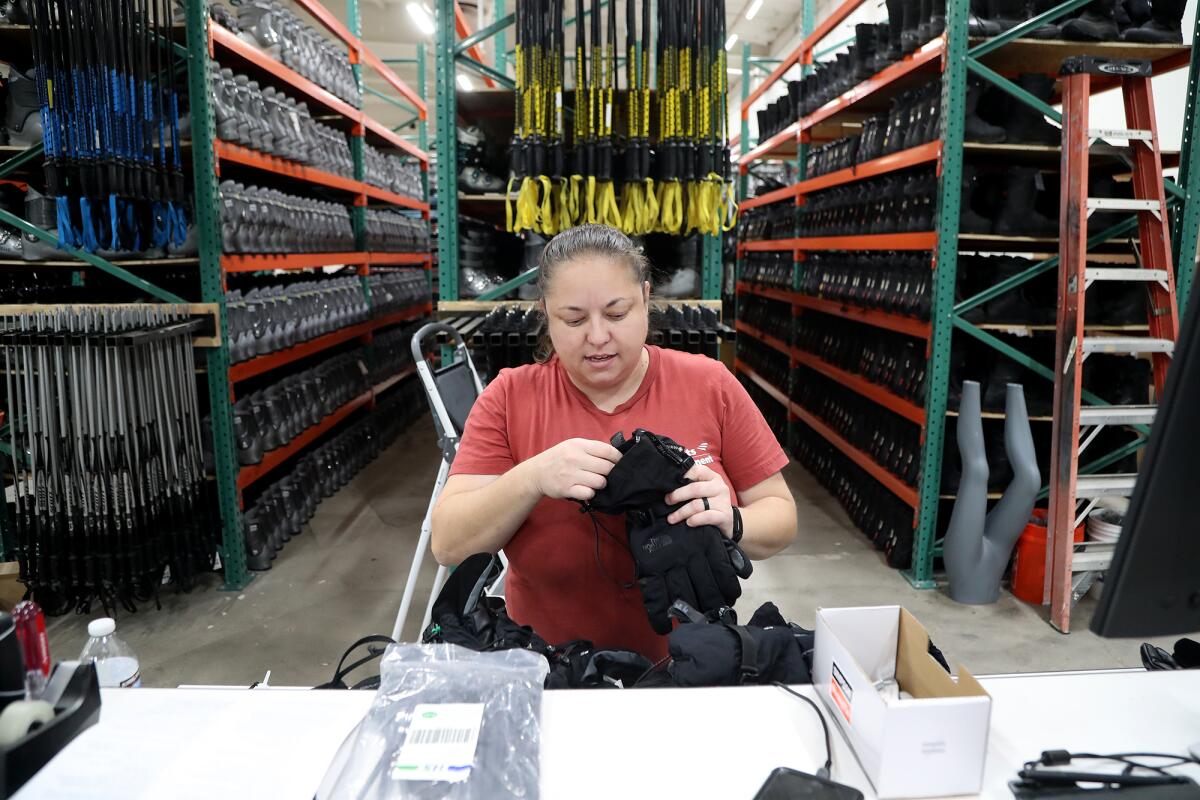 Teryn Sain, rentals manager, unpacks and sorts out snow gloves at the Sports Basement in Fountain Valley on Wednesday.
