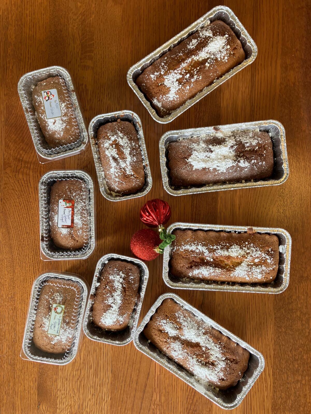 Loaves of cake sit in tins on a table, with a Christmas ornament among them.