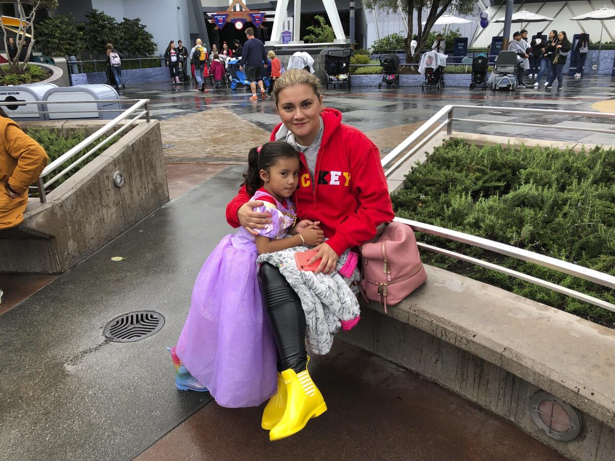 Andrea Vizcarra y su hija de 4 años, María José, de México, posan para una foto en el parque Disneyland en Anaheim, California, el viernes 13 de marzo de 2020. Ellas y su familia planearon pasar aquí más días de vacaciones, pero sus planes se volcaron cuando Disney y Universal cerraron para frenar el avance del nuevo coronavirus. (AP Foto/Amy Taxin)