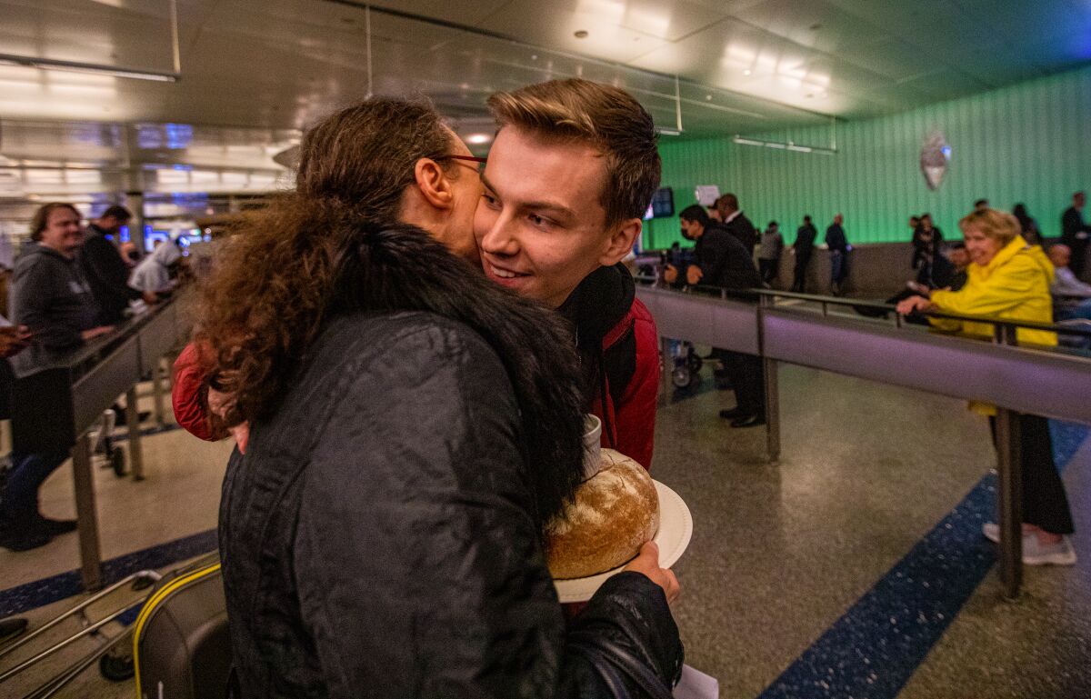 A woman hugs a young man arriving at LAX