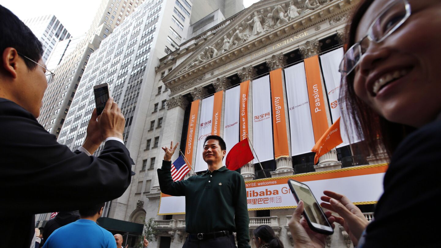 Arthur Jiang of Beijing poses for a photograph in front of the New York Stock Exchange on the day of Alibaba's initial public offering.