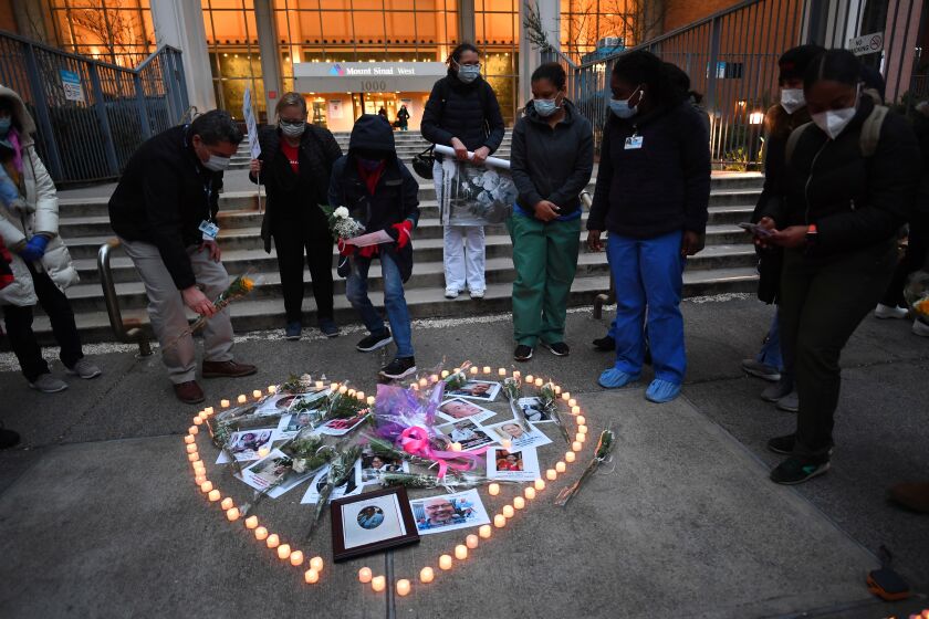 Nurses and healthcare workers light candles as they mourn and remember their colleagues who died during the outbreak of the novel coronavirus (which causes COVID-19) during a demonstration outside Mount Sinai Hospital in Manhattan on April 10, 2020 in New York City. - The global coronavirus death toll topped 100,000 on April 10 as Easter celebrations around the world kicked off in near-empty churches with billions of people stuck indoors to halt the pandemic's deadly worldwide march. (Photo by Johannes EISELE / AFP) (Photo by JOHANNES EISELE/AFP via Getty Images)