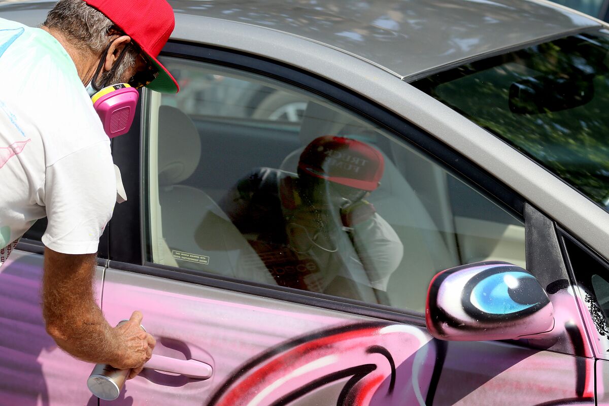 Kenny Scharf paints a Prius pink at the Karbombz! rally Saturday. 