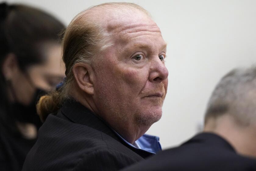 FILE - Celebrity chef Mario Batali, center, is seated at Boston Municipal Court during the first day of his pandemic-delayed trial, Monday, May 9, 2022, in Boston. Batali pleaded not guilty to a charge of indecent assault and battery in 2019, stemming from accusations that he forcibly kissed and groped a woman after taking a selfie with her at a Boston restaurant in 2017. Now, Batali has agreed to settle two Massachusetts lawsuits that accused the celebrity chef of sexual assault, attorneys for the women said on Wednesday, Aug. 24, 2022. (AP Photo/Steven Senne, Pool, File)