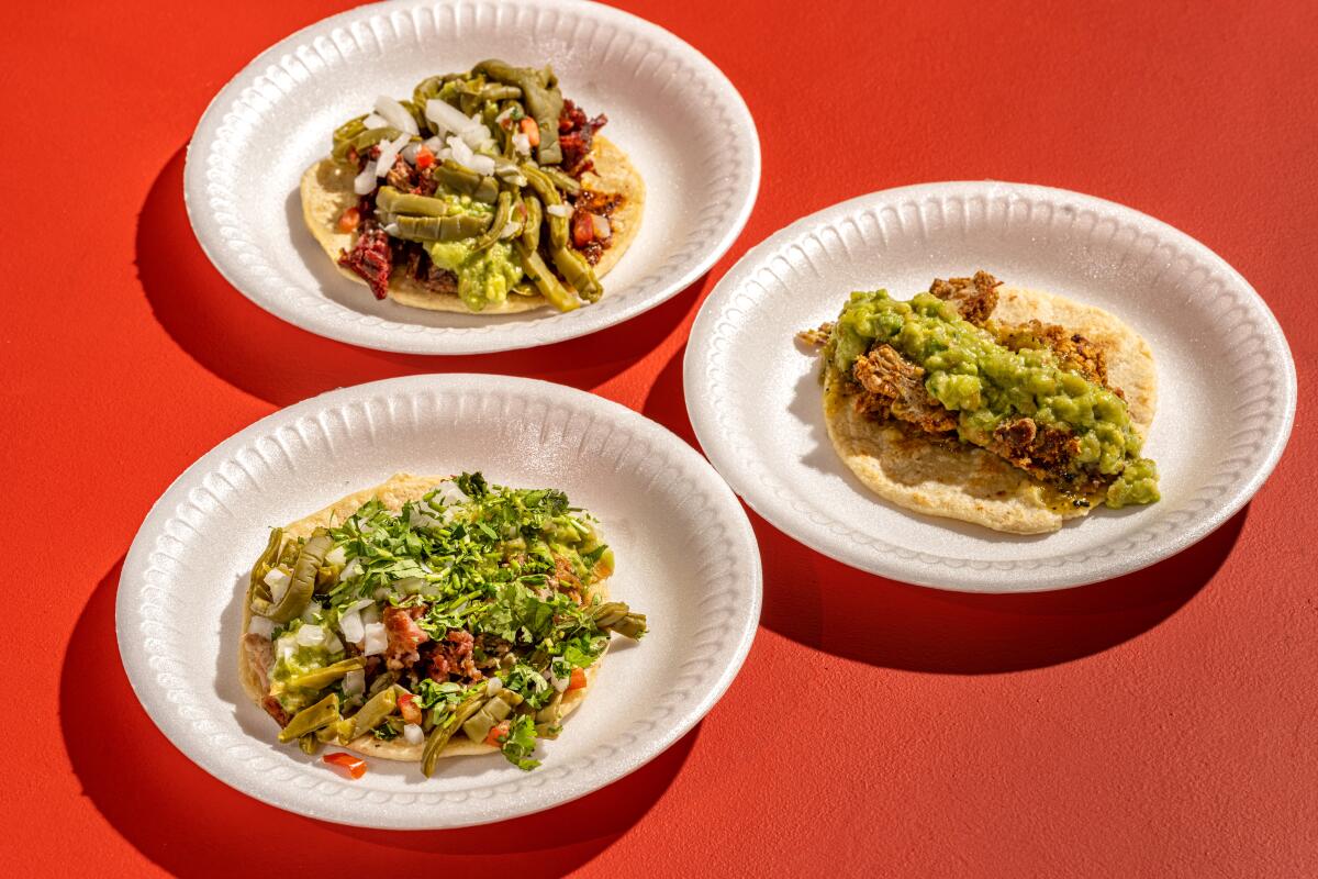 Three open tacos on white styrofoam plates
