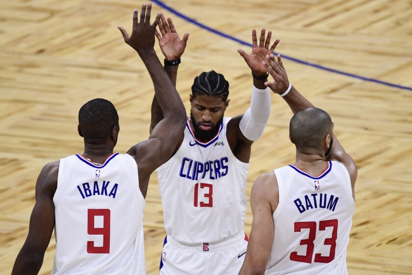 Clippers' Paul George celebrates with teammates Serge Ibaka and Nicolas Batum.