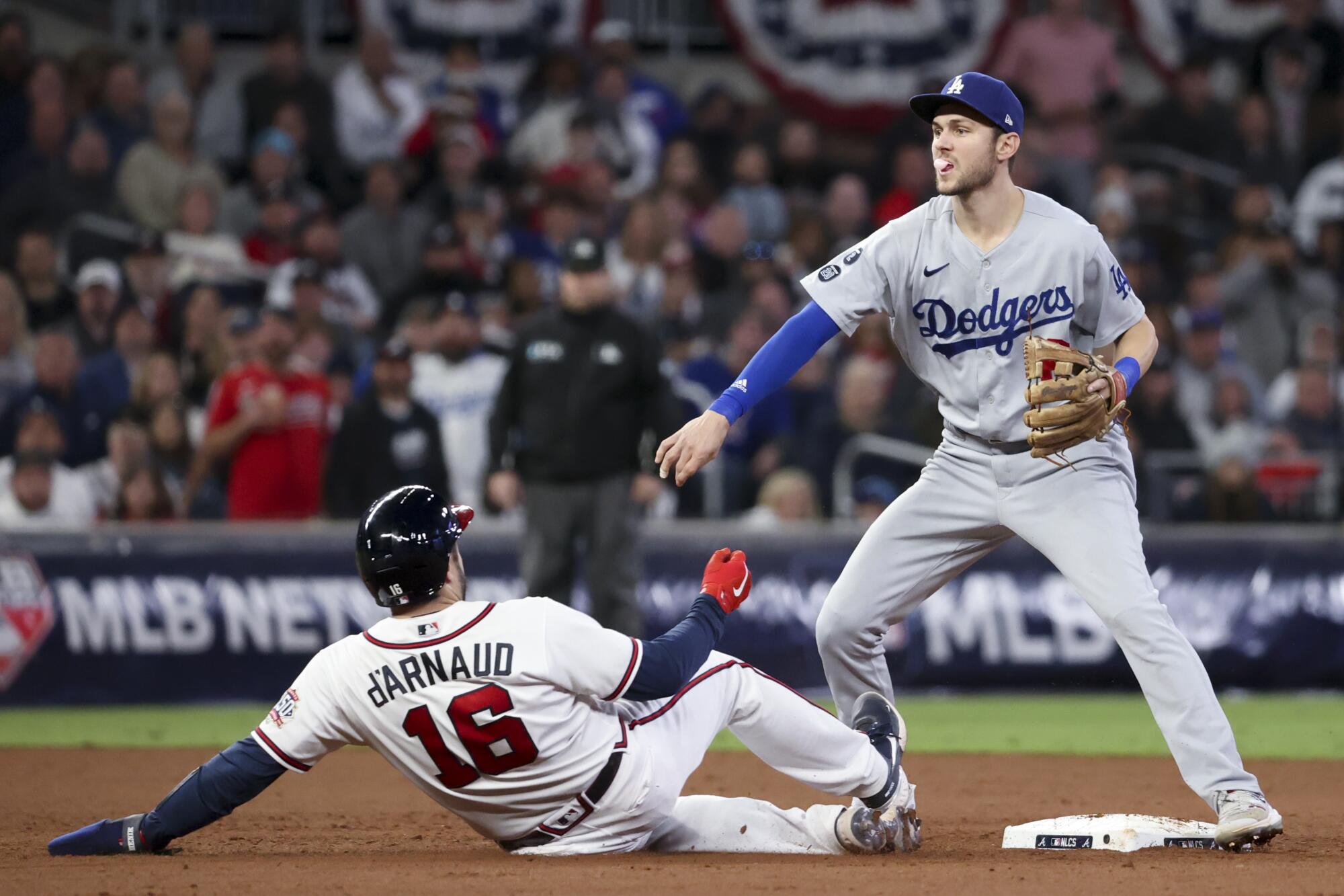 Dodgers second baseman Trea Turner, right, throws to first after forcing out Braves' Travis d'Arnaud