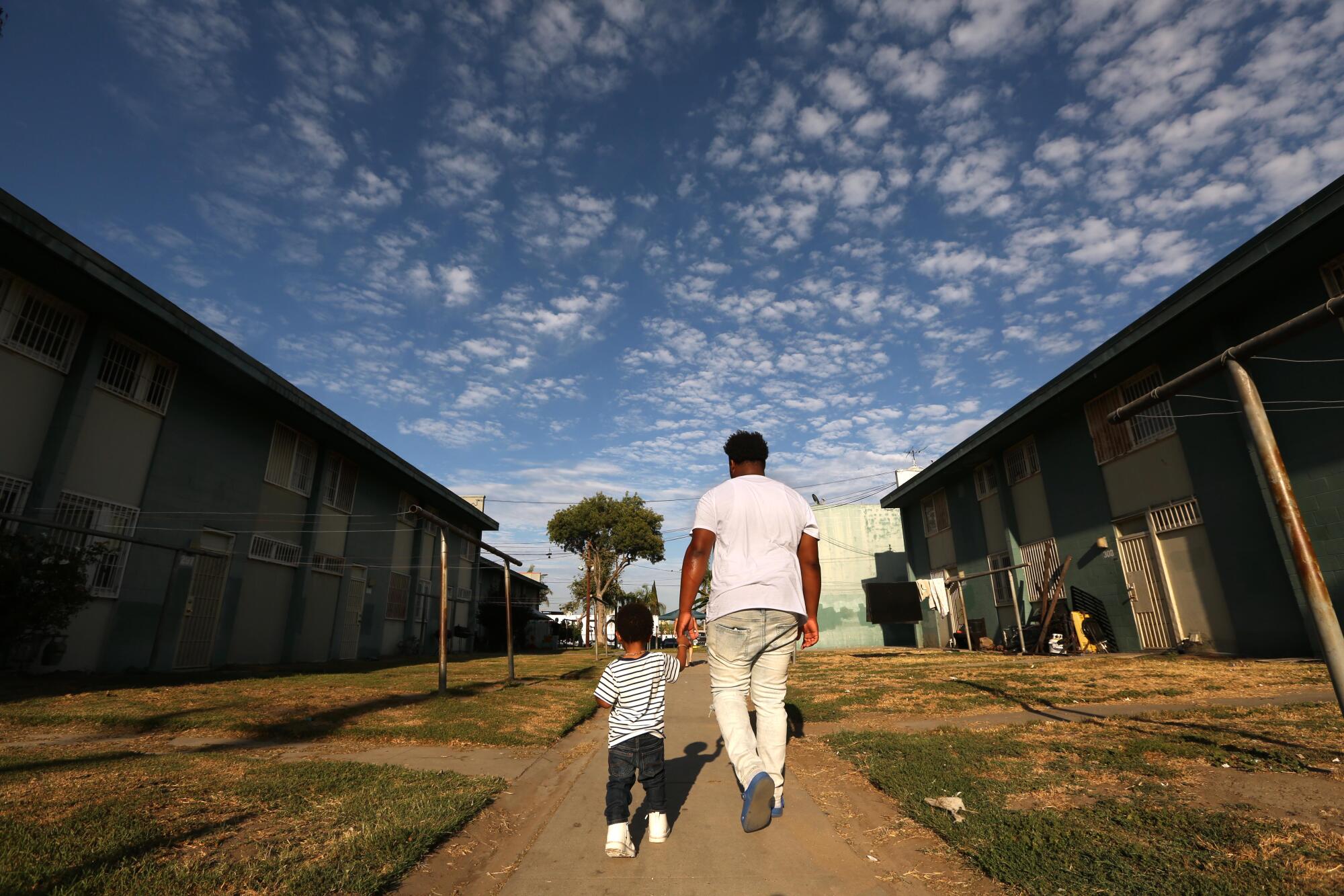 Daylyn Busters, 17, walks with his nephew Ah'Kari George, 1, at the Imperial Courts housing project in Watts.