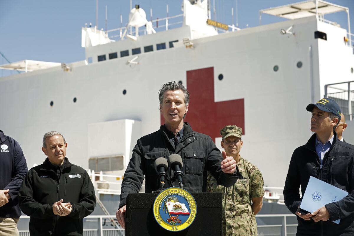 Gov. Gavin Newsom, center, with Los Angeles Mayor Eric Garcetti, right, in front of the Navy hospital ship Mercy at the Port of Los Angeles. 