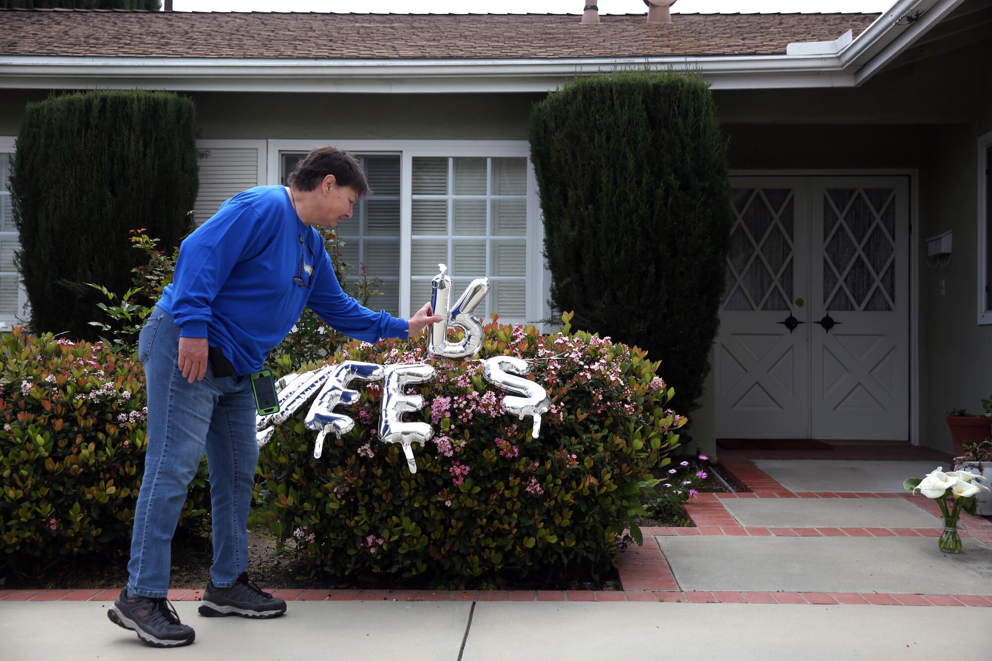 Jean Lionelli fixes a sign hung outside neighbors Harry and Libby Palakow's home in Granada Hills to celebrate their 70th wedding anniversary.