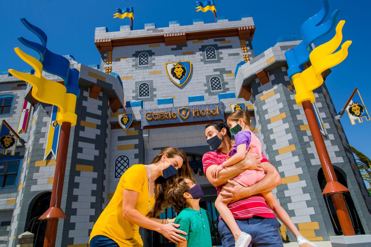 A family wears masks outside the Legoland Castle Hotel.
